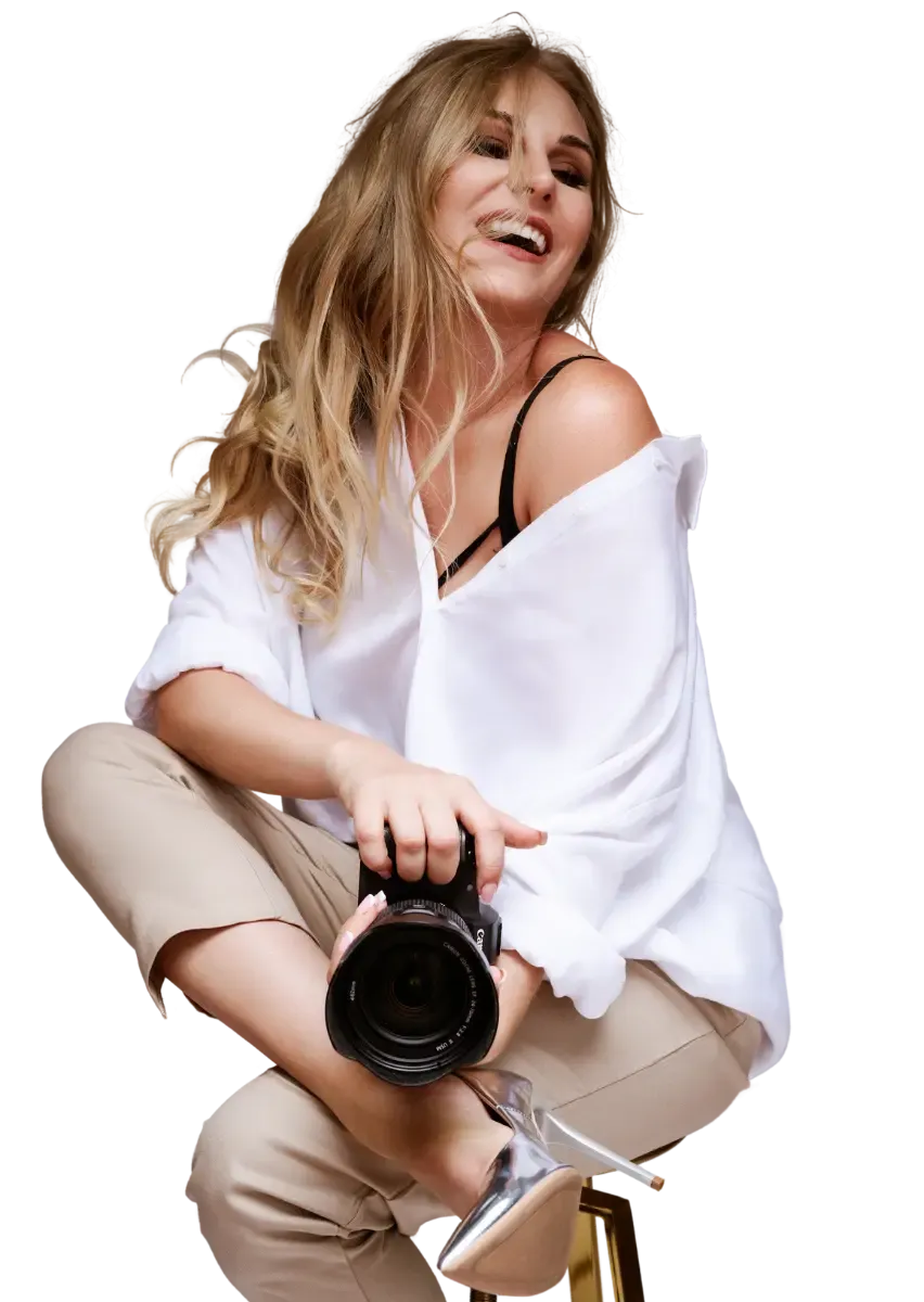 Monika Kapelewska in a white shirt, laughing, a camera in her hands.